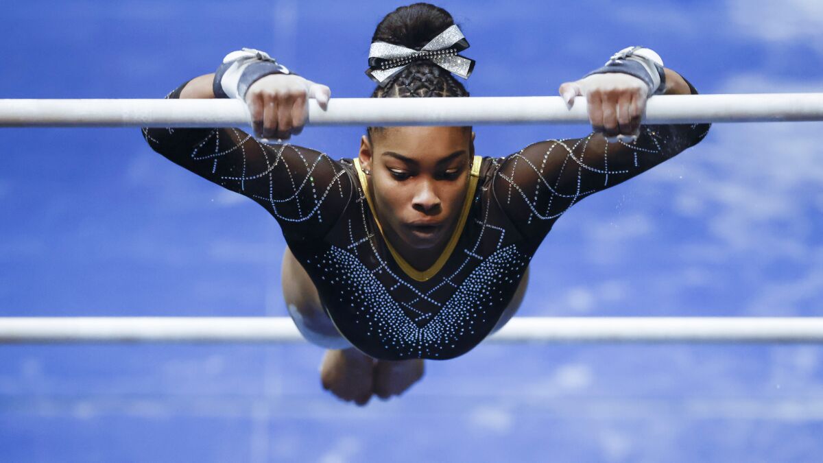 A gymnast swings from a bar.