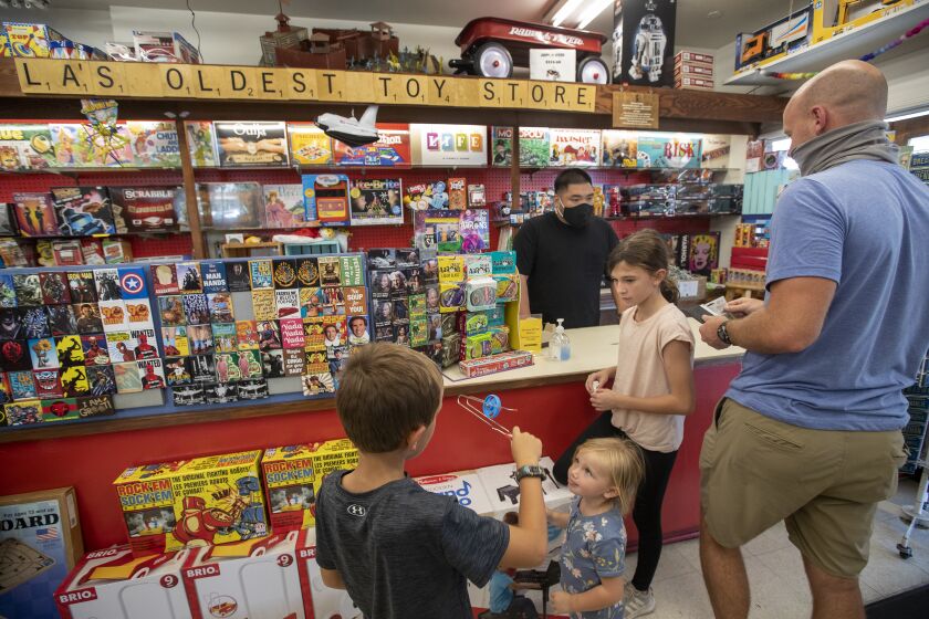 LOS ANGELES, CA - SEPTEMBER 22: Left to right-Jack Norris, 7, his sisters Avery, 2, and Harper, 9, along with their father Lance, visit Kip's Toyland located inside the Old Farmer's Market in Los Angeles. Behind the counter is store manager Jay Ortiz. Kip's Toyland was founded in 1945 by war veteran Irvin "Kip" Kipper, and is now run by his son Don Kipper and granddaughter Lily Kipper. (Mel Melcon / Los Angeles Times)