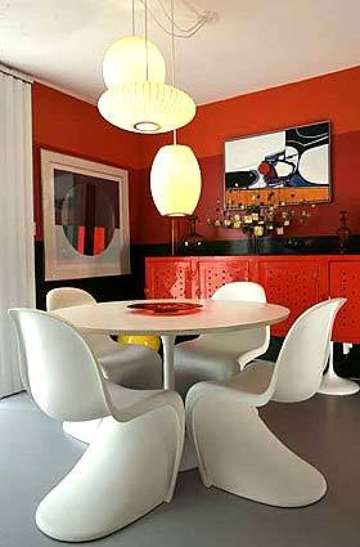 A striped wall, a Saarinen-style trumpet-base table and an orange credenza crafted from old pool lockers reel in the years in Leon Gazarians dining area, above. Designer Jan Appleton, below, hung chrome pendants in a Doheny Estates home.