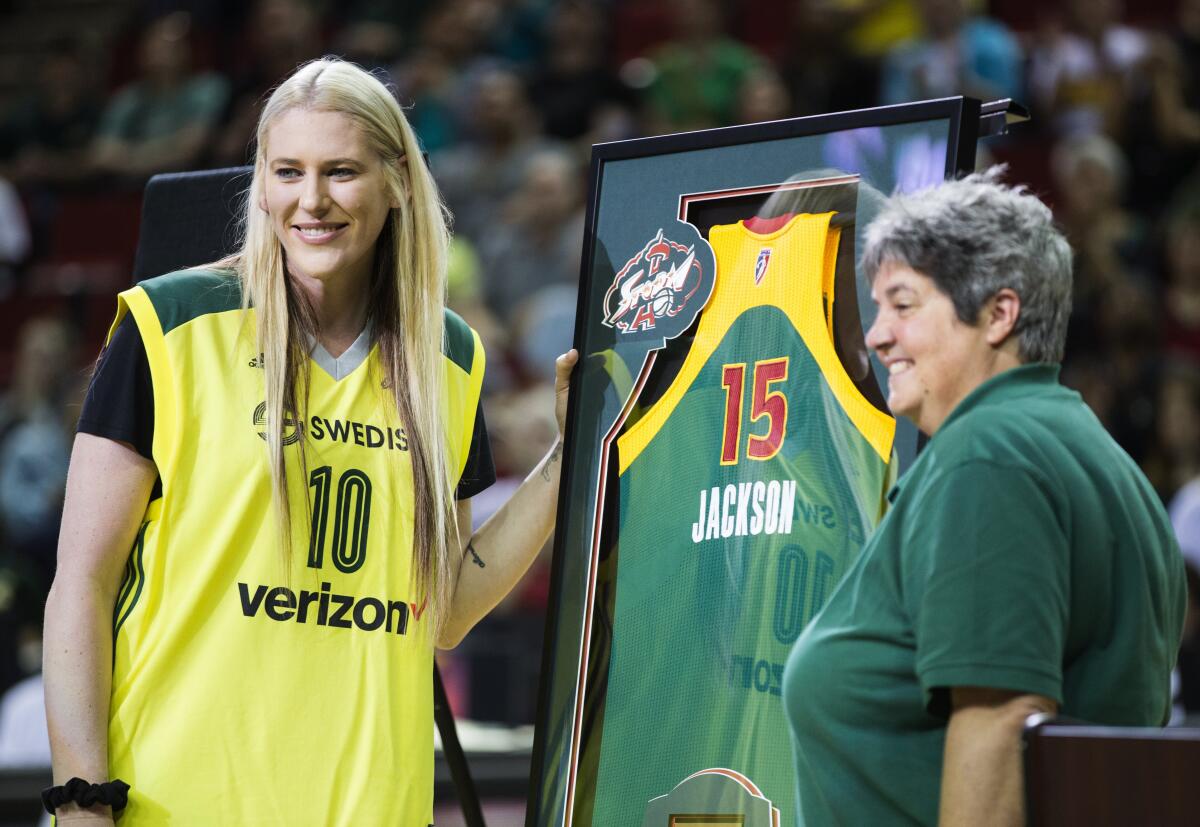 FILE - Lauren Jackson, left, is presented with a jersey by Seattle Storm co-owner Lisa Brummel after the Storm defeated the Washington Mystics 80-51 in a WNBA basketball game, Friday, July 15, 2016, in Seattle. The team formally retired her jersey No. 15. The jersey was unveiled in the arena's rafters, next to the two banners signifying the WNBA championships she helped win in 2004 and 2010. Jackson is savoring every minute of her basketball comeback, in 2022, even though the battle-tested Australian hoops icon knows she can't do things that once captivated fans before retiring from the sport in 2016. (Lindsey Wasson/The Seattle Times via AP, File)