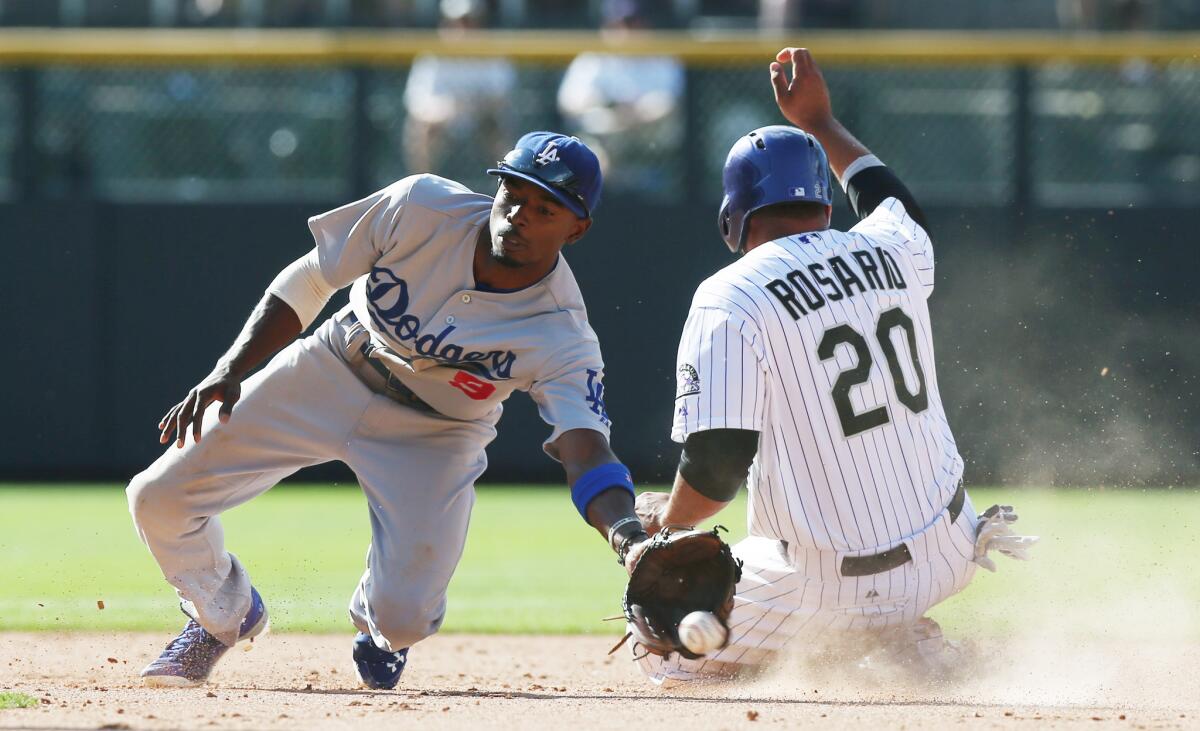 Dodgers second baseman Dee Gordon, left, fields the throw as Colorado's Wilin Rosario advances to second on a wild pitch in the eighth inning of the Rockies' 8-7 victory on Saturday.