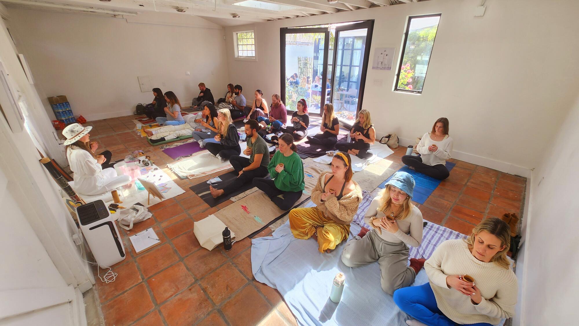 People sit on the floor of a study holding cups.