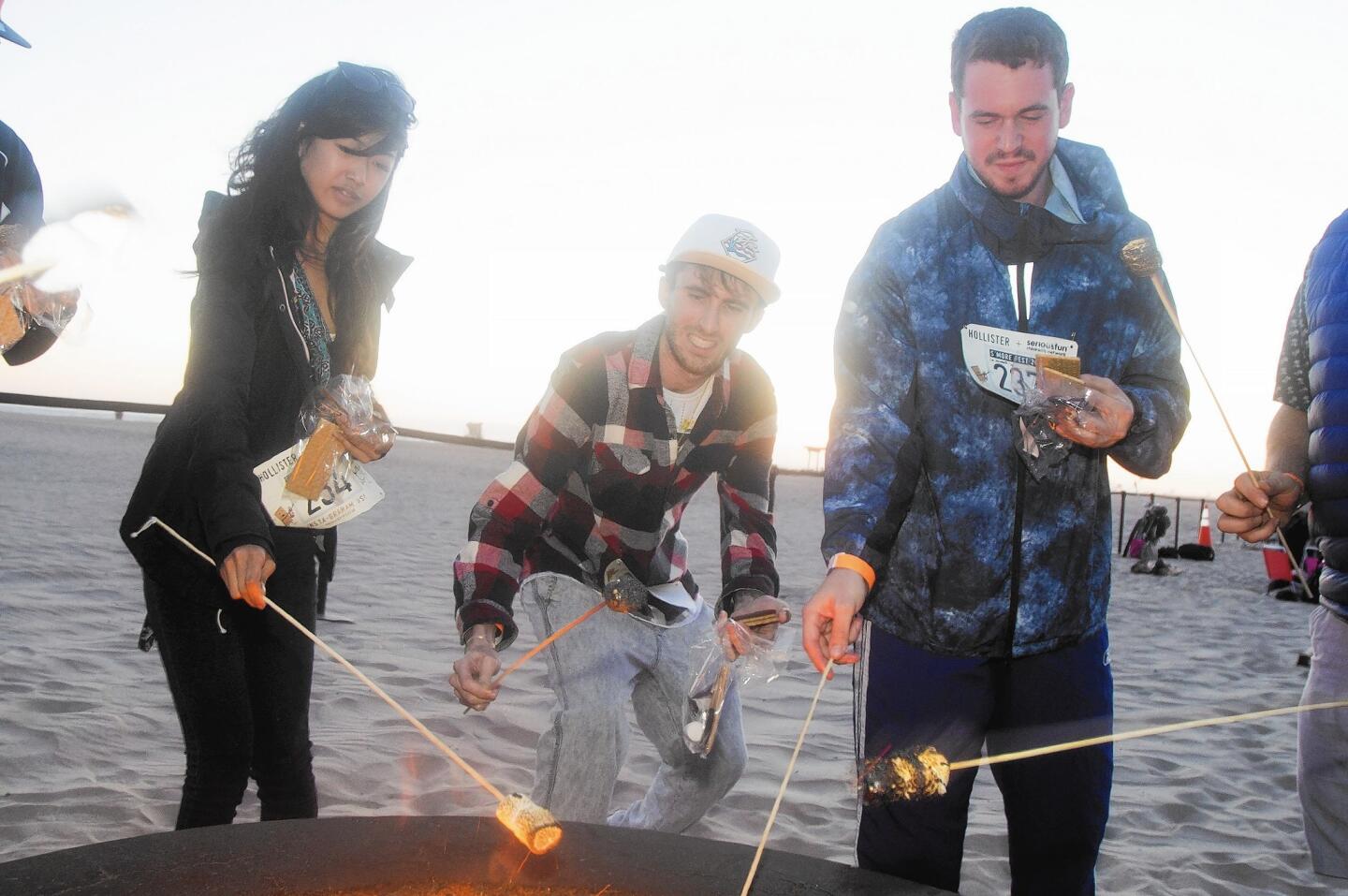 From left, Nini Almero, Blake Ducote and Max Wafel attempt to break the world record for making the most s'mores at once in Huntington Beach Thursday evening.