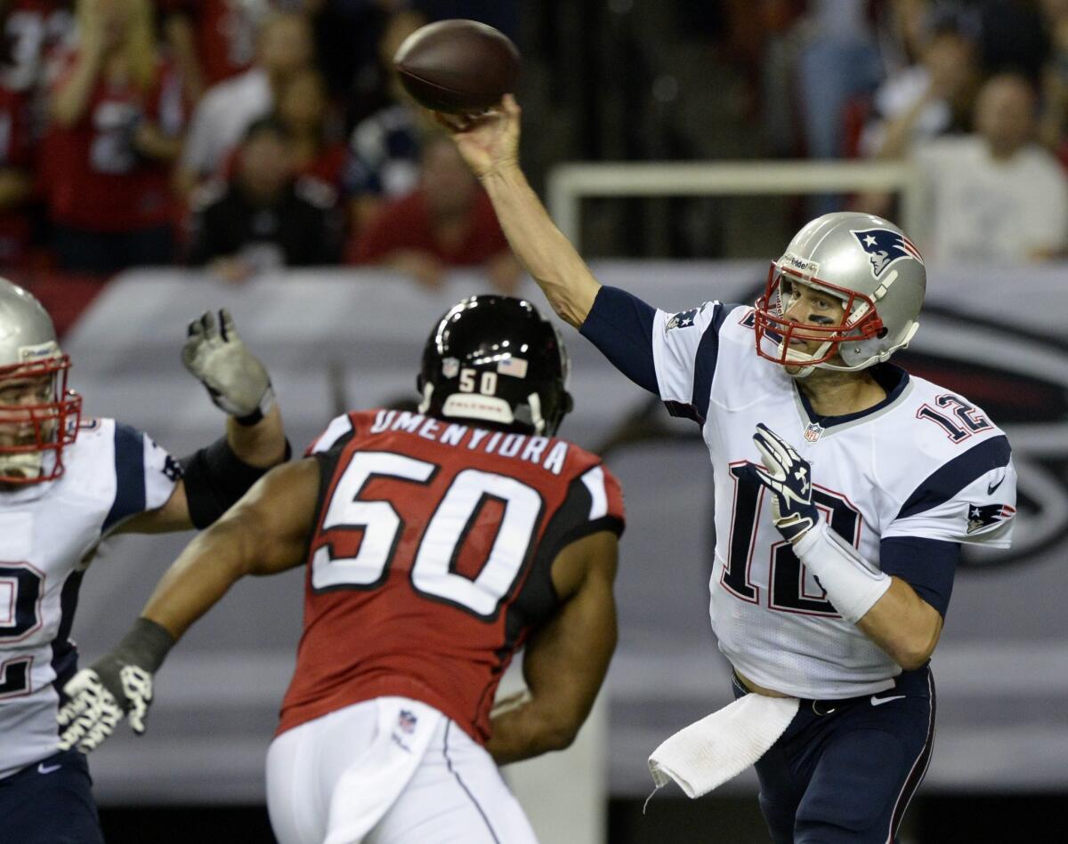 New England Patriots quarterback Tom Brady passes the ball under pressure from Atlanta Falcons defensive end Osi Umenyiora.
