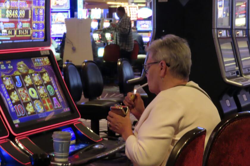 A gambler lights a cigarette at a slot machine in Harrah's casino in Atlantic City N.J., on Sept. 29, 2023. On Monday, April 29, 2024, Atlantic City's main casino workers union asked a judge to let it intervene in that lawsuit. (AP Photo/Wayne