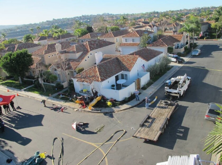 The wreckage of the four-seat Robinson R44 helicopter that crashed against a Newport Beach home is seen from a firetruck ladder Jan. 30, 2018.