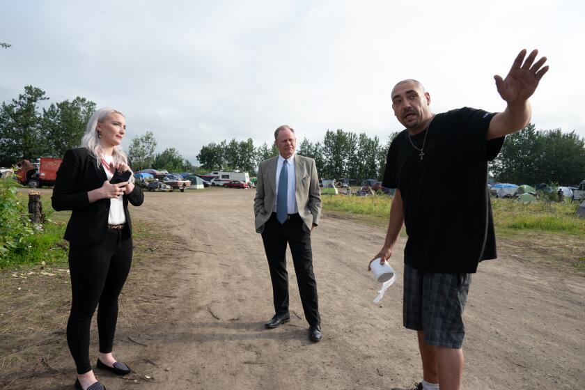 Anchorage Mayor Dave Bronson, center, listen to Ingra homeless camp resident “Joel”