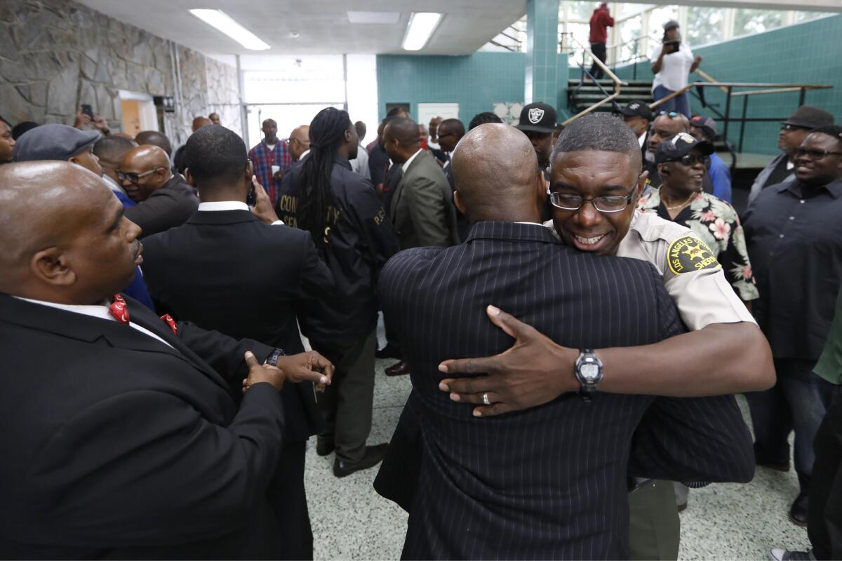 L.A. County Deputy Sheriff Rafer Owens, who's also a pastor, hugs a member of the Nation of Islam as current and former gang members work toward a cease-fire. (Genaro Molina / Los Angeles Times)