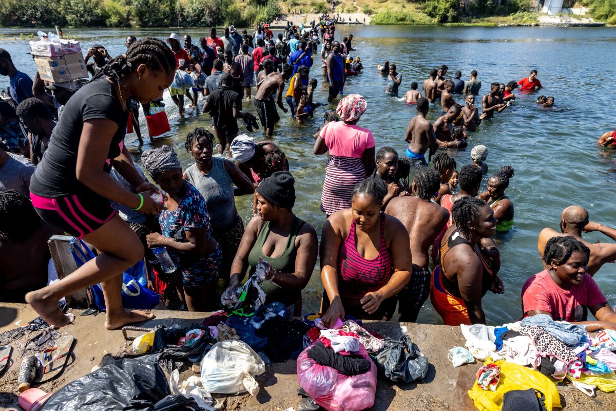 Migrants wash their clothes in the Rio Grande River under the International Bridge between Del Rio, Texas, and Acuña, Mexico,