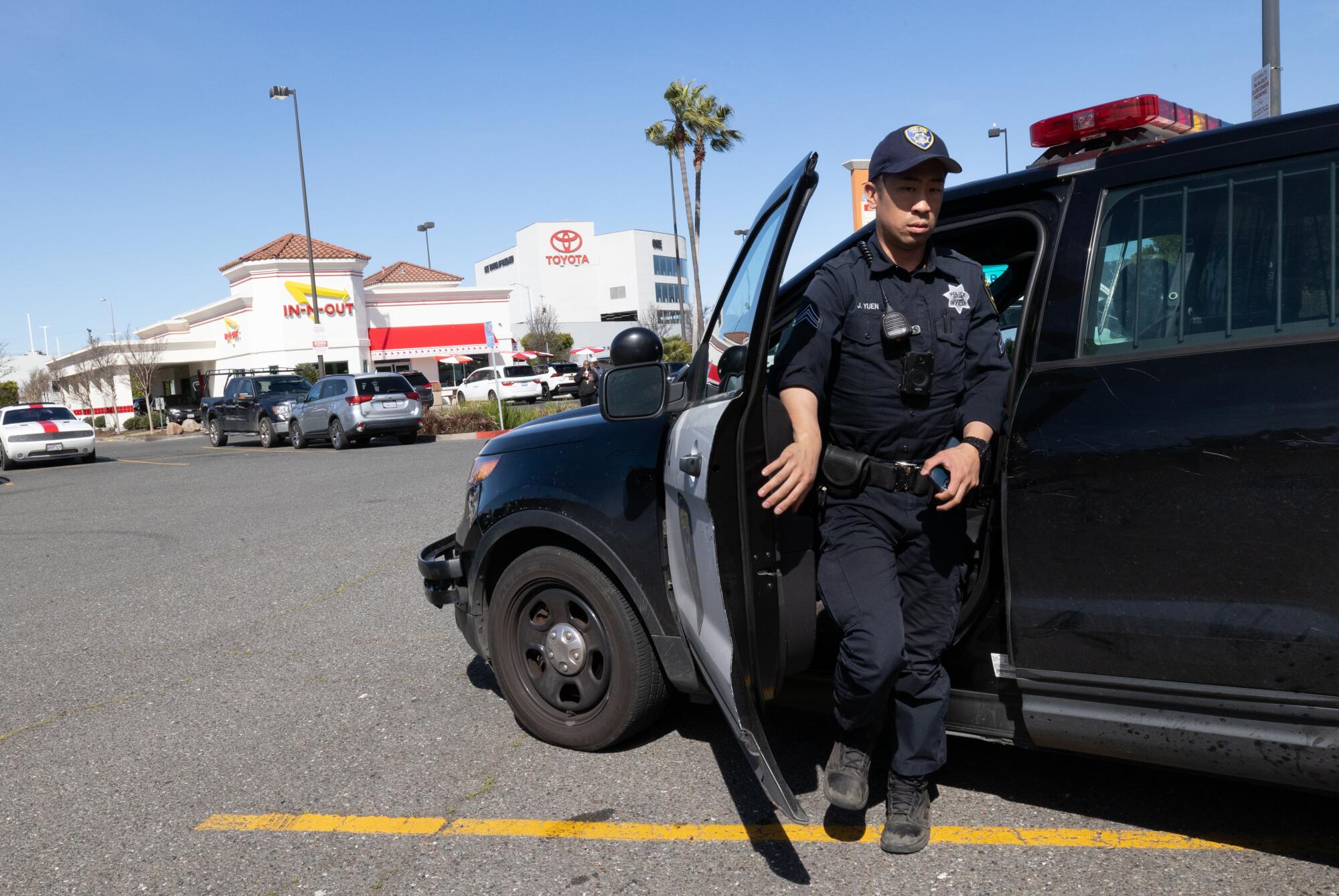 Oakland Police officer J. Yuen leaves his car while on patrol at the In-N-Out restaurant in Oakland.