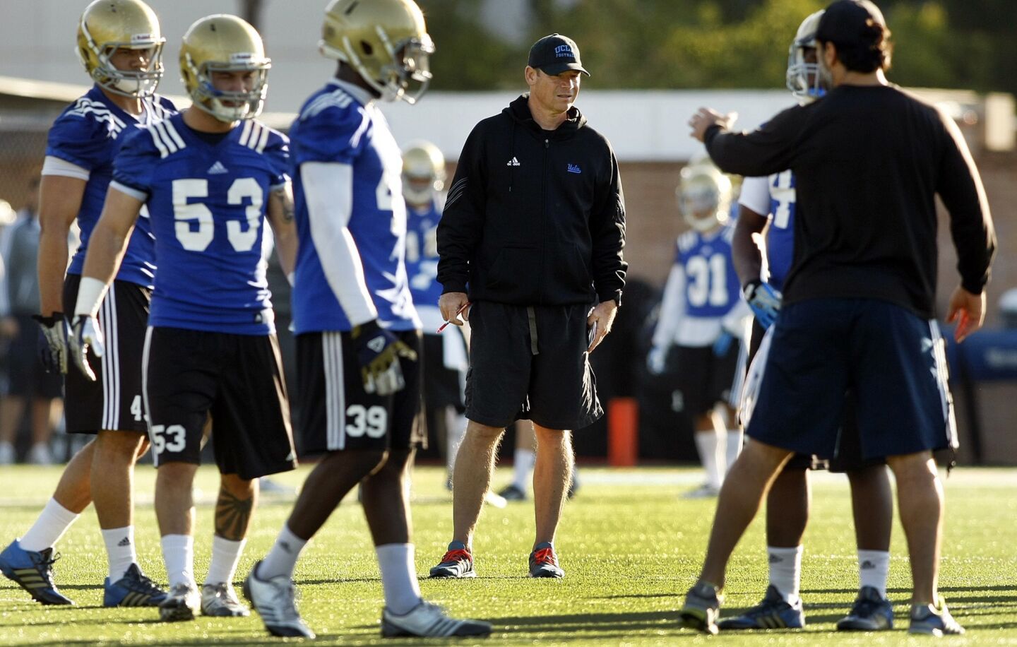 UCLA Coach Jim Mora, center, watches his Bruins practice Tuesday morning during the team's first spring practice.