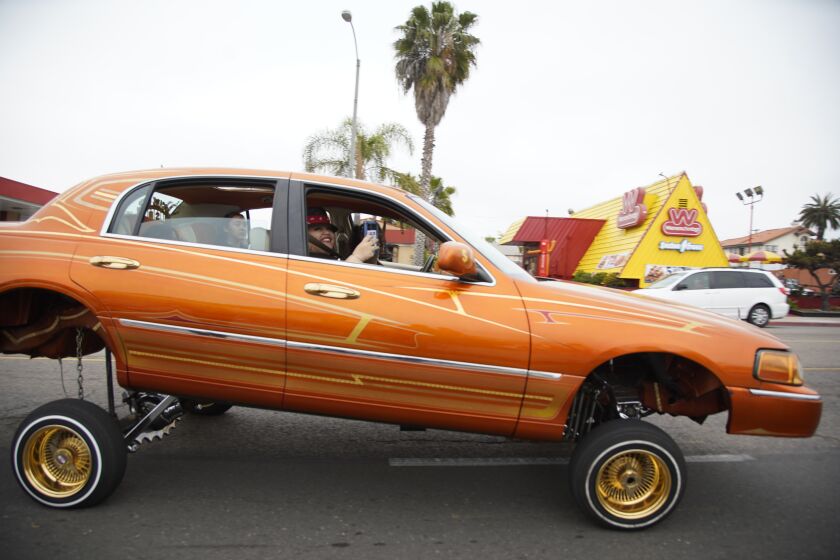 Lowriders drive down Highland Avenue in celebration of the last no-cruising street sign being removed in National City as the ban is lifted on Friday, May 19, 2023.