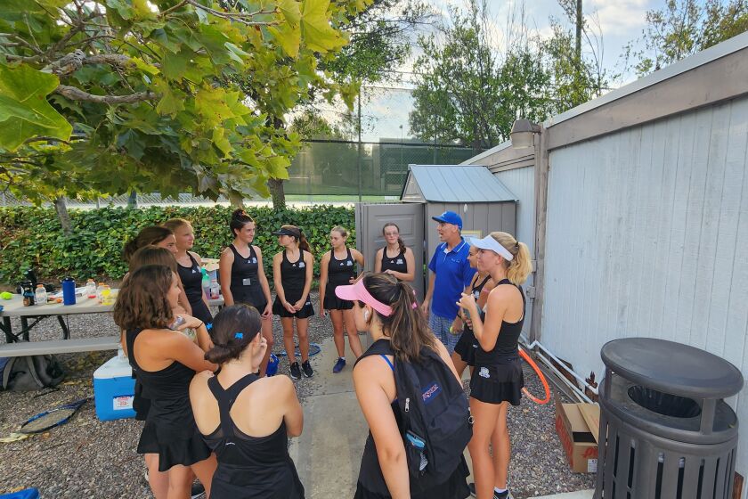 Coach Troy Romero talks to the Bulldogs girls tennis team after the victory again Fallbrook on Sept. 13.