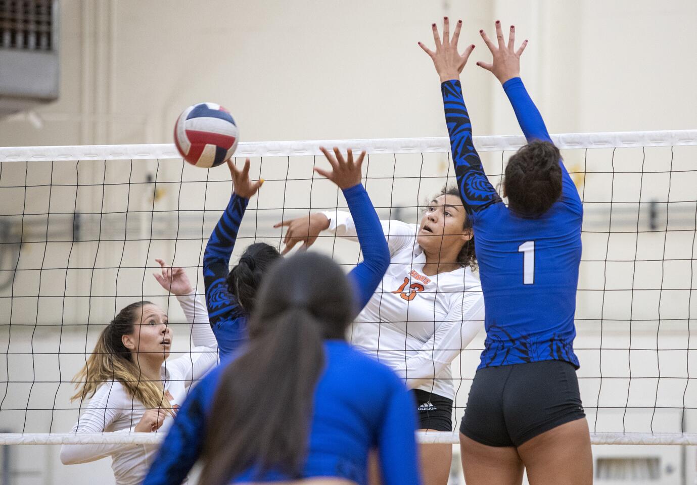 Huntington Beach's Olivia Carlton hits against Bingham's Journey Tupea, left, and Jada Suguturaga during a match at the Dave Mohs Memorial volleyball tournament at Newport Harbor on Saturday, September 1.