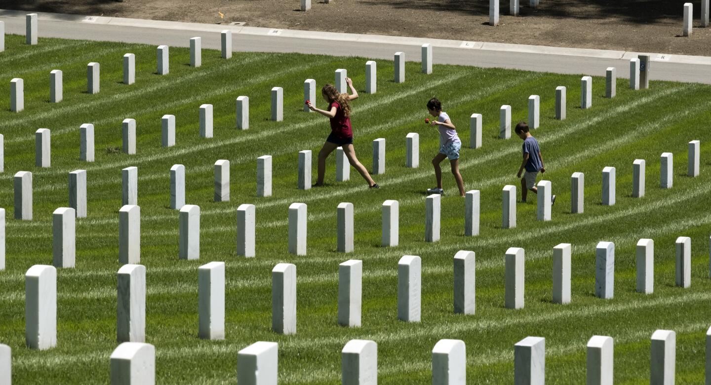 Children place a flowers at the graves of fallen soldiers Monday at the Los Angeles National Cemetery to honor fallen soldiers and healthcare workers in Los Angeles. The general public was not able to attend the annual Memorial Day cemetery commemoration due to the coronavirus outbreak.