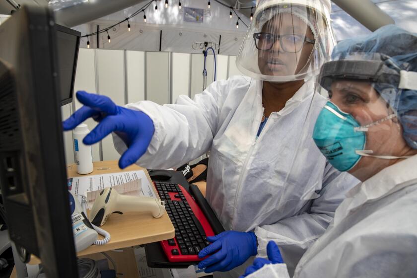 MISSION HILLS, CA - JULY 10: Nurses Janil Wise (CQ), left, and Melinda Gruman, right, look over medical chart for a patient who is pregnant and was exposed to a person with COVID-19, in the OB triage tent at Providence Holy Cross Medical Center on Friday, July 10, 2020 in Mission Hills, CA. (Brian van der Brug / Los Angeles Times)