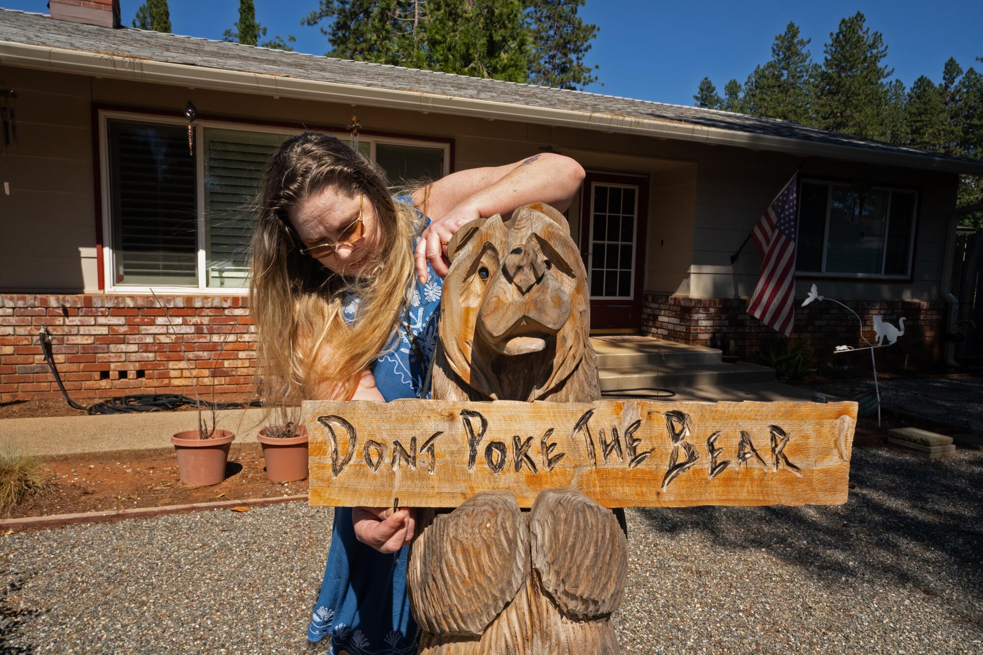 A woman adjusts a sign in front of her home.
