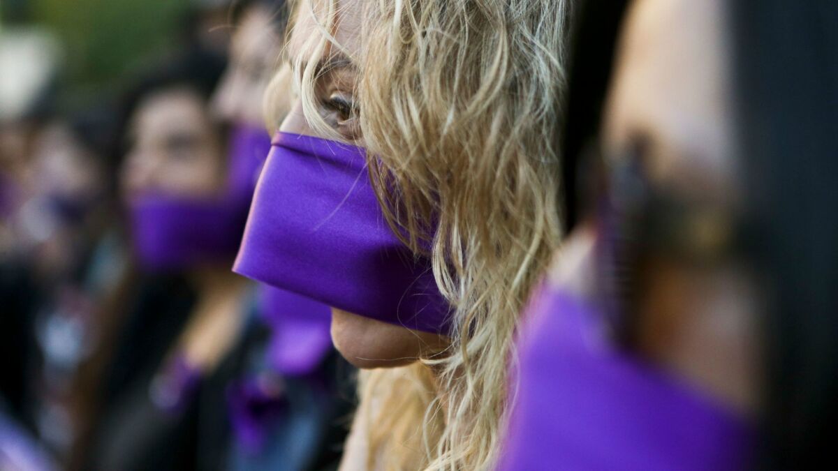Santiago, Chile: Women wear purple ribbons over their mouths during the "Todas en Silencio" demonstration in front of La Moneda presidential palace.