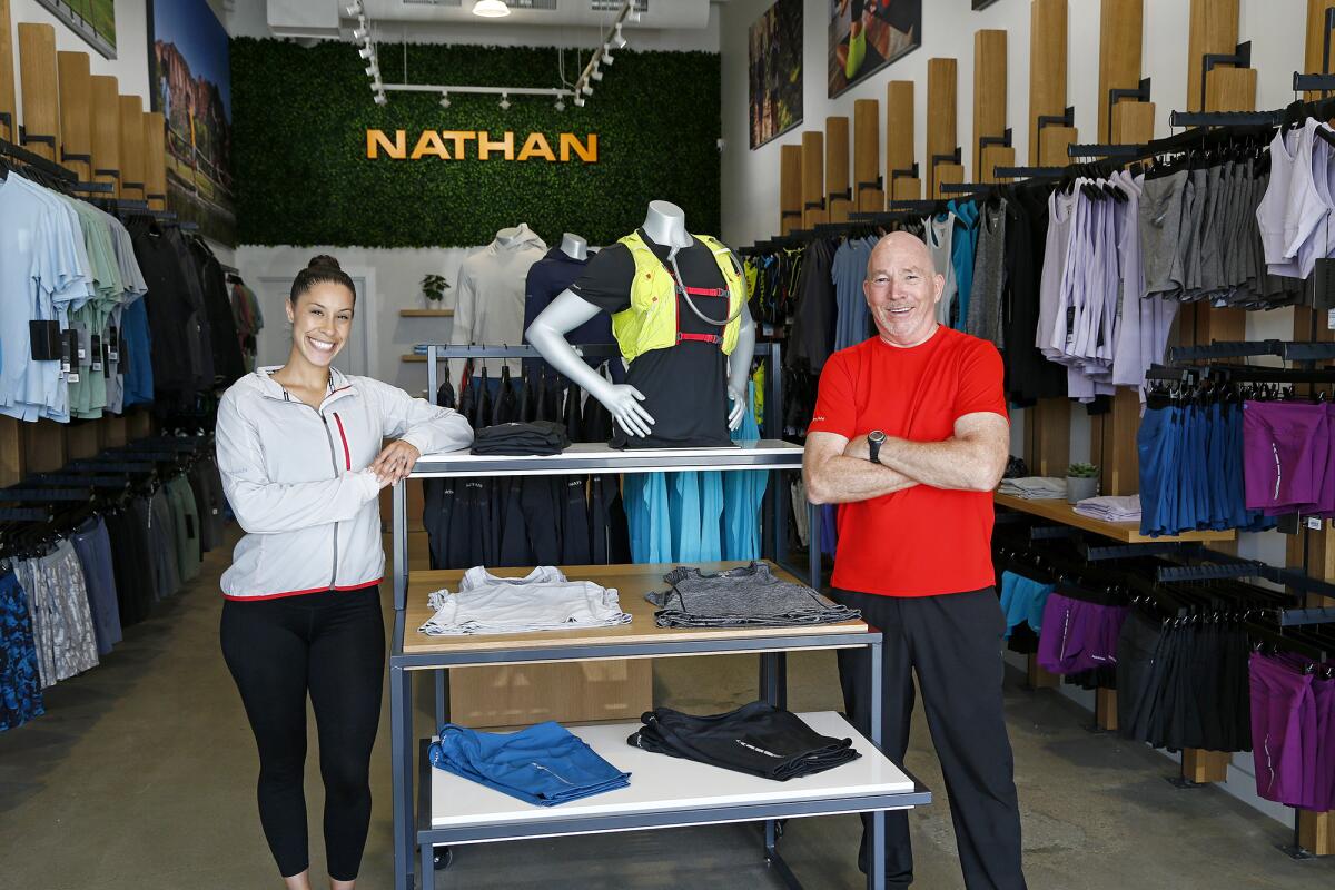 Store manager Rob Hanson and assistant manager Andrea Vazquez stand inside Nathan Sports in Costa Mesa.