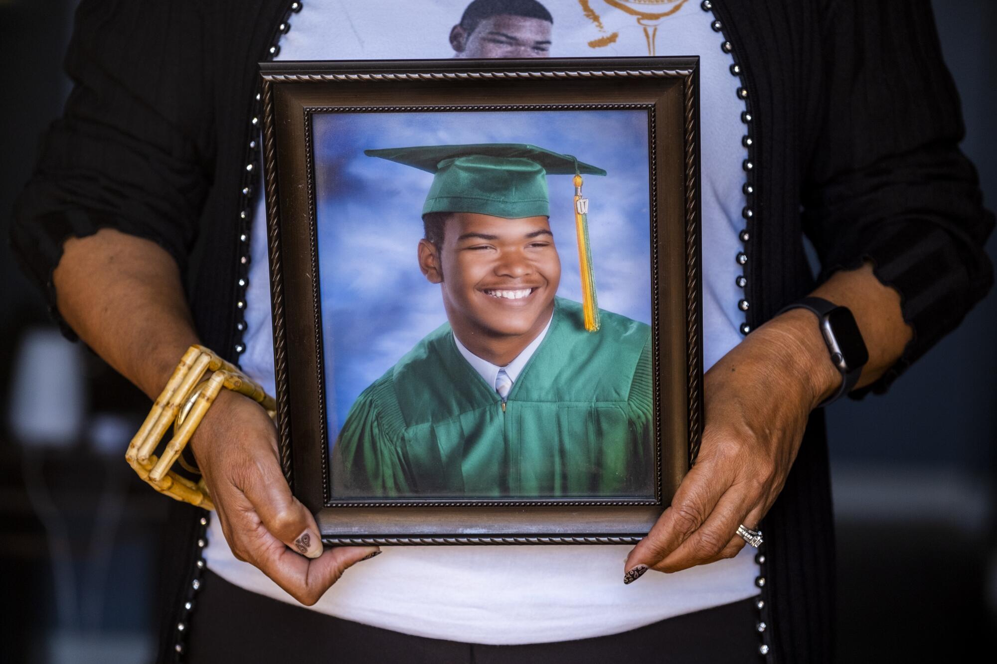Hands hold a portrait of Julian Alexander in his graduation cap and gown