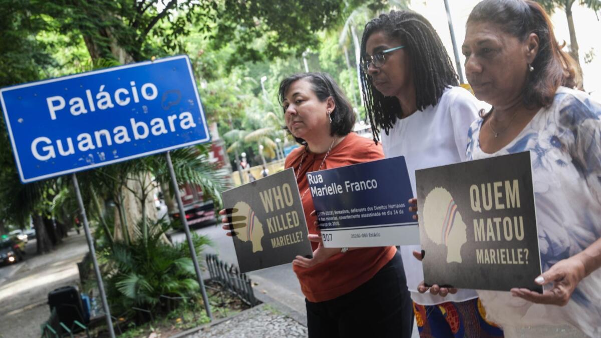 Executive Director of Amnesty International USA Margaret Huang, left, director of Amnesty International Brazil Jurema Werneck and mother of Marielle Franco, Marinete Silva, hold signs that read "Who killed Marielle?"