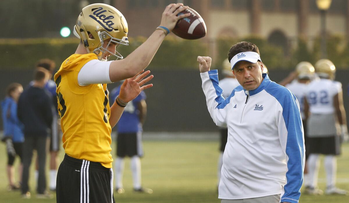 Jedd Fisch, right, the new UCLA football offensive coordinator, works with quarterback Matt Lynch during a spring practice on the campus Thursday.