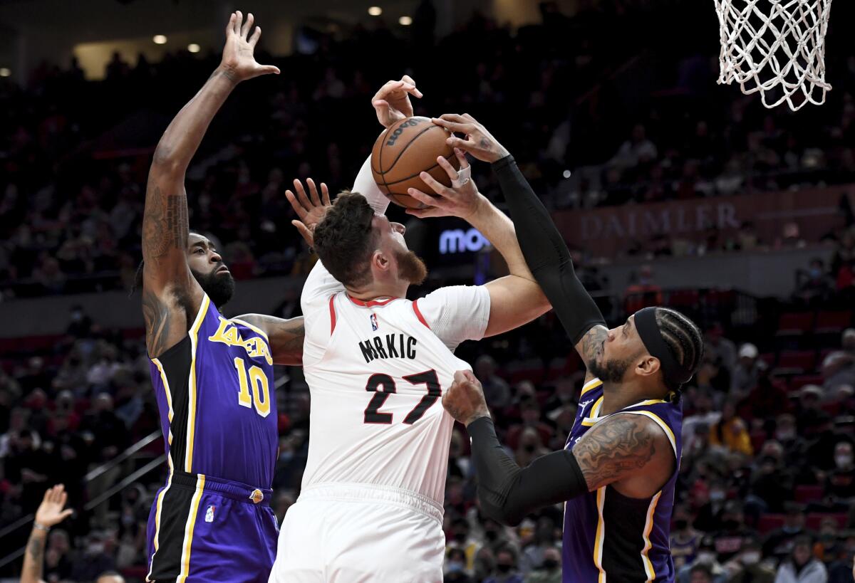 Portland's Jusuf Nurkic (27) is fouled by the Lakers' Carmelo Anthony, right, as teammate DeAndre Jordan, left, defends.