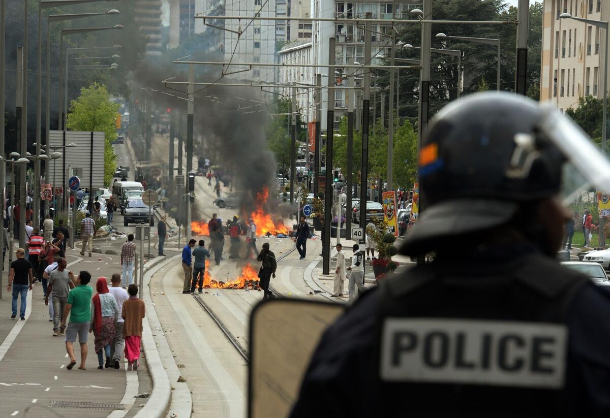 A French riot police officer looks at burning barricades along the tramway line in Sarcelles, a suburb north of Paris, on Sunday.