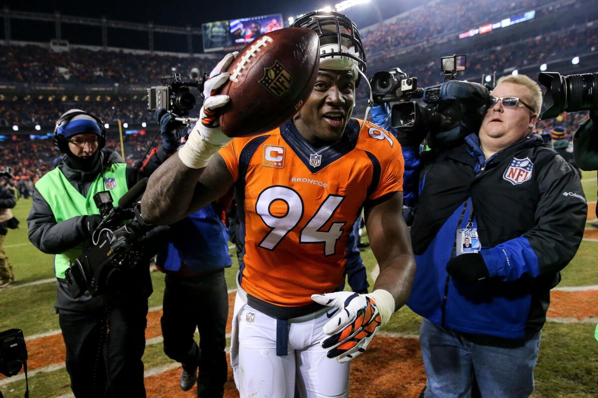 Broncos outside linebacker DeMarcus Ware walks off the field smiling and holding a football after recovering a fumble to end the game against the Bengals.