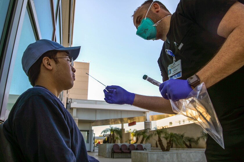 A healthcare worker administers a coronavirus PCR test to a person.