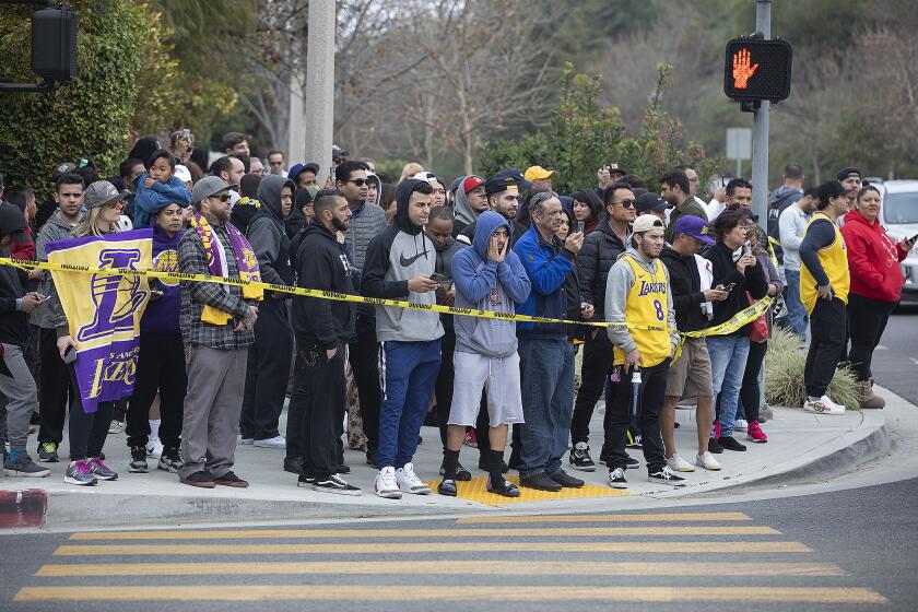 CALABASAS, CA-JANUARY 26, 2020: People gather on Las Virgenes Road in Calabasas near the scene of a helicopter that crashed and burst into flames Sunday morning amid foggy conditions in the hills above. All people aboard were killed including Los Angeles Lakers legend Kobe Bryant. (Mel Melcon/Los Angeles Times)