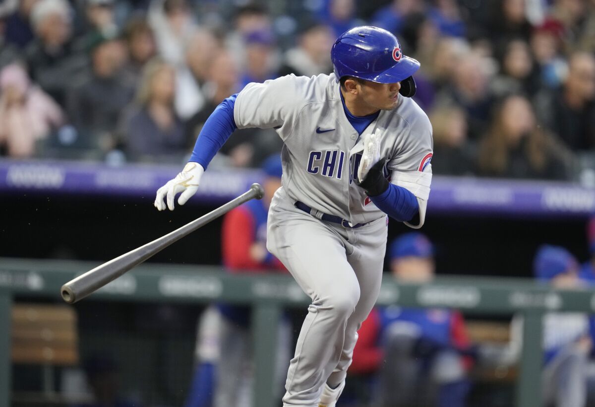 Chicago Cubs' Seiya Suzuki heads to first base as Colorado Rockies shortstop Jose Iglesias mishandles the ball for an error in the third inning of a baseball game Thursday, April 14, 2022, in Denver. (AP Photo/David Zalubowski)