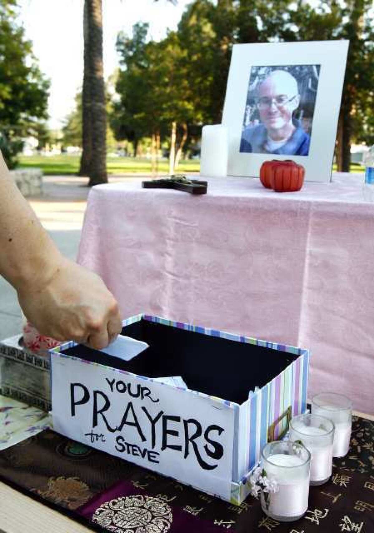 One of the guests drops a prayer he wrote into a prayer box at a prayer vigil for FBI agent Stephen Ivens at McCambridge Park in Burbank. Ivens' body was found by two hikers.