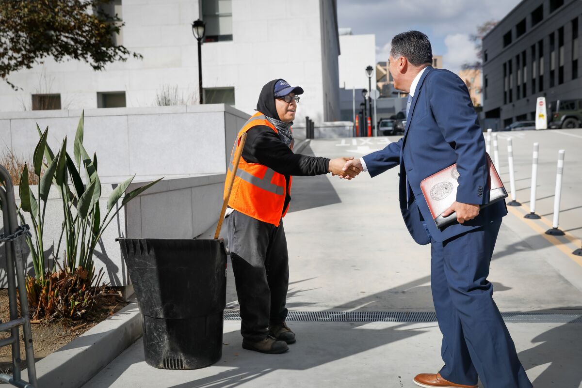 Sheriff-elect Robert Luna, right, shakes hands with landscape worker Juan Argueta, left.