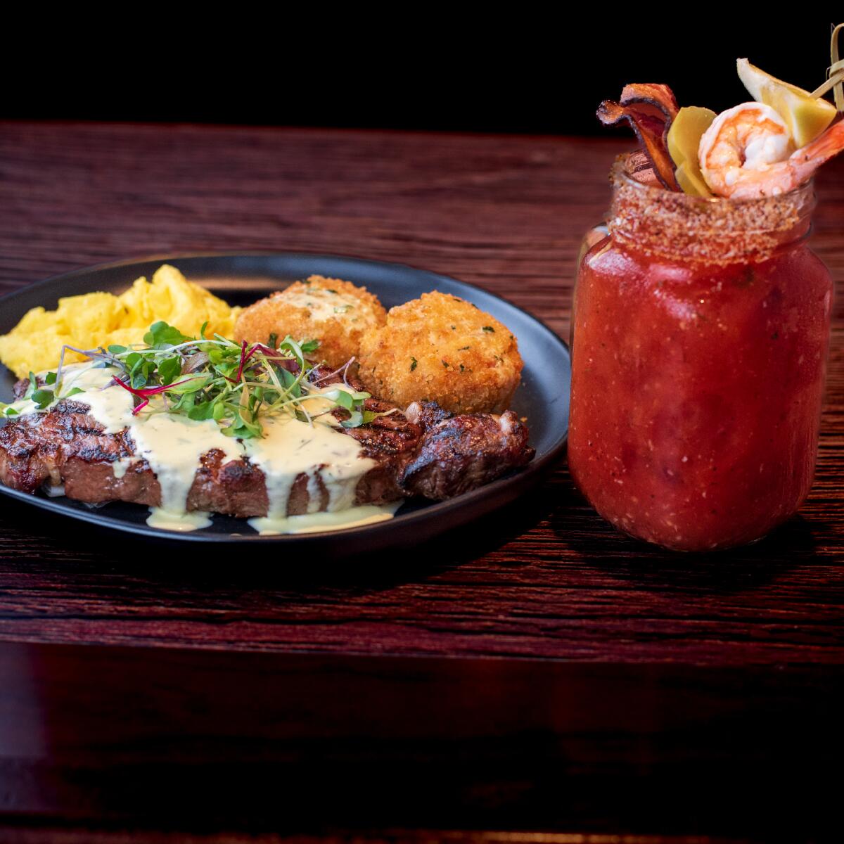 A rib-eye steak with scrambled eggs, a lobster fritter and a bloody mary on the side from Black Angus.