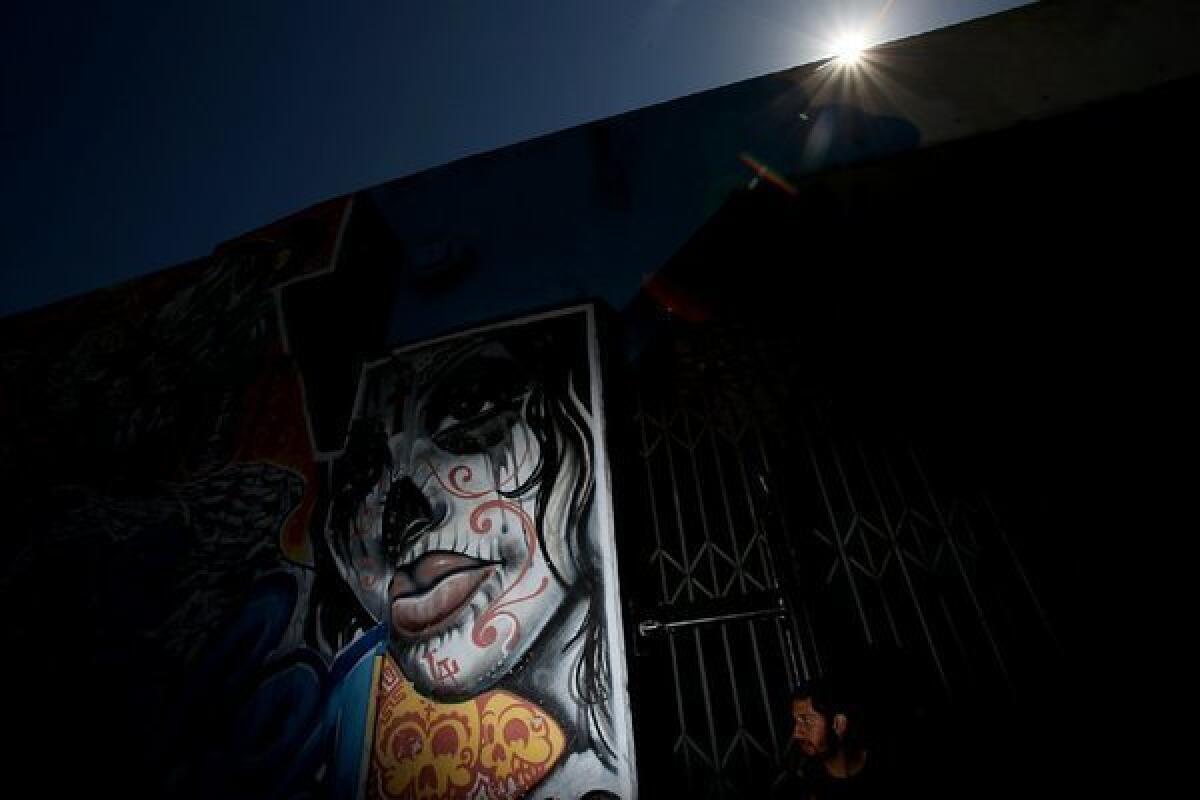 A man walks past graffiti art on the exterior of a warehouse in the downtown Los Angeles Arts District.