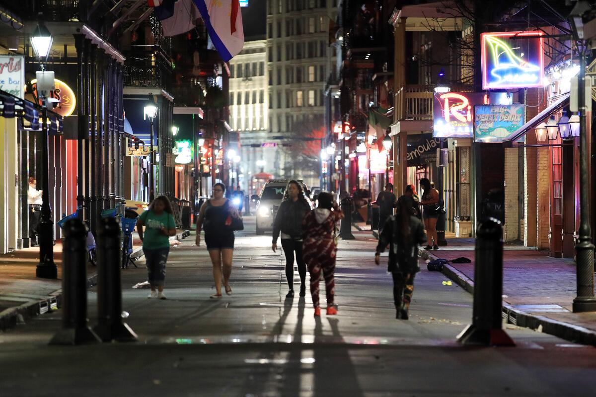 People walk down Bourbon Street in New Orleans just before an order comes down for bars, gyms and casinos to close until April 13.
