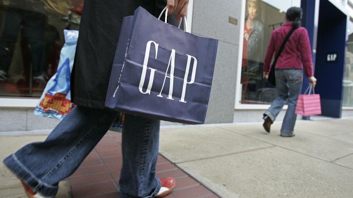 A shopper carries a bag from a Gap store.