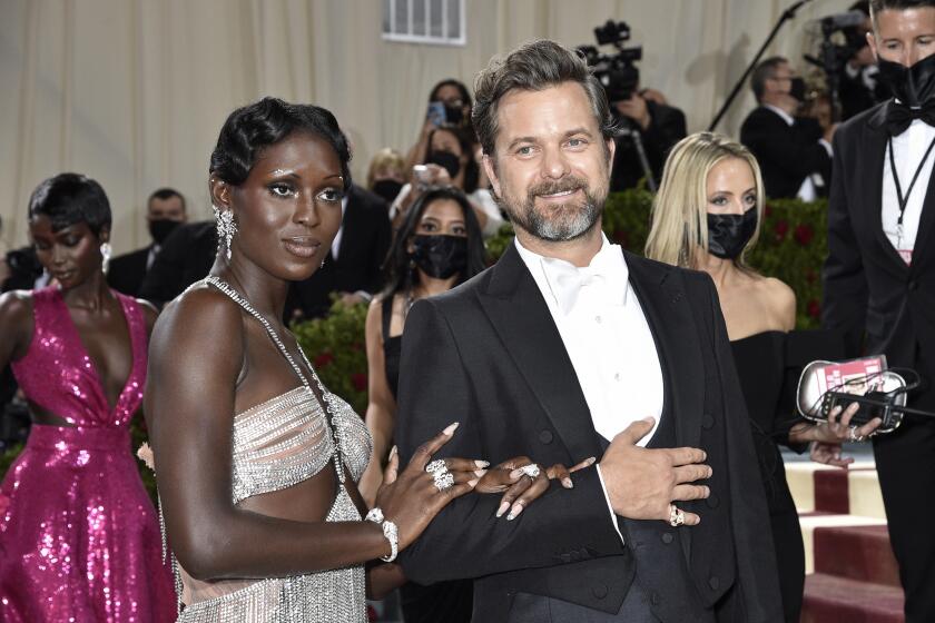 Jodie Turner-Smith in a metallic cut-out gown holding and  next to Joshua Jackson in a tuxedo at the Met Gala
