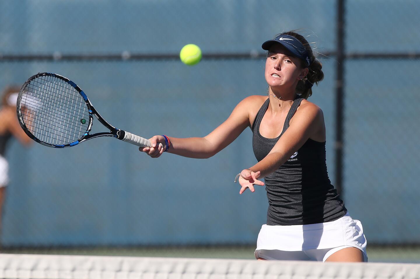Newport Harbor High's Riley DeCinces steps into a winning volley as she plays in doubles match with partner Sterling Solomon in girlsâ€™ non-league tennis match against Troy on Wednesday.
