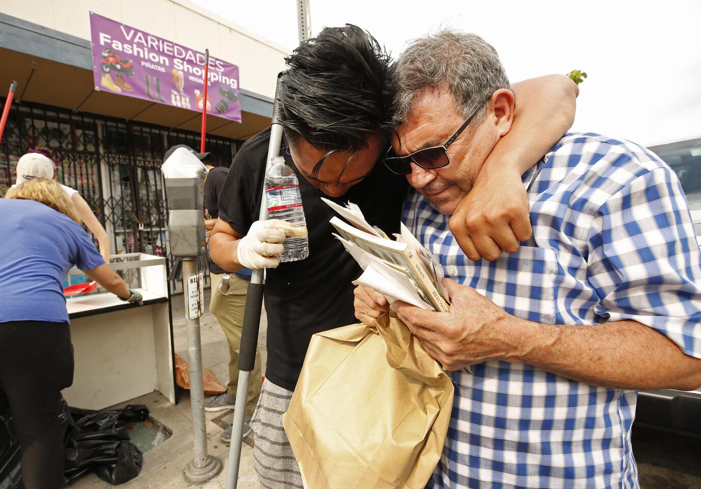Ibn Kadalim hugs shop owner Larry Contreras during the clean-up.