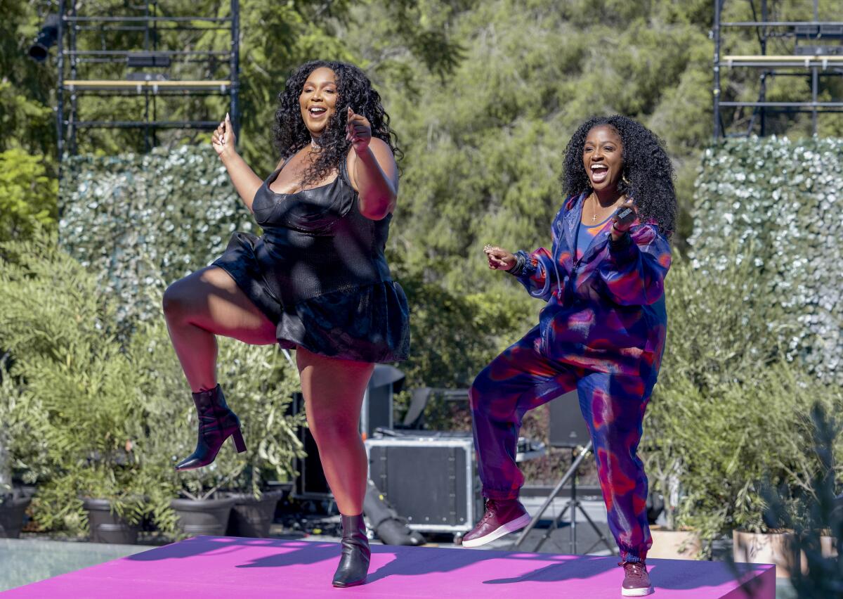 Two women dance on an outdoor stage.