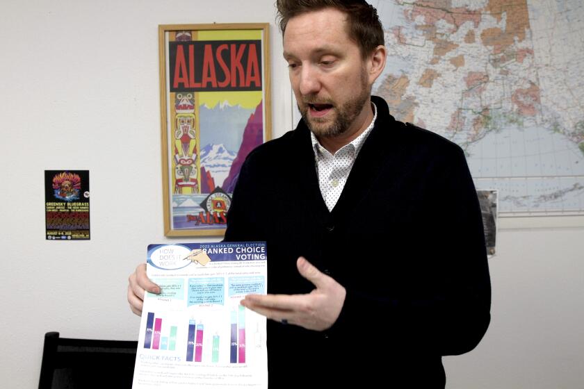 Former Alaska lawmaker Jason Grenn holds an Alaska Division of Elections brochure explaining ranked choice voting at his office in Anchorage, Alaska, on Friday, Jan. 14, 2022. Grenn was sponsor of a ballot initiative passed by Alaska voters in 2020 that would end party primaries and send the top four vote-getters, regardless of party affiliation, to the general election, where ranked-choice voting would determine a consensus winner. The model is unique among states and viewed by supporters as a way to encourage civility and cooperation among elected officials. The Alaska Supreme Court is set to hear arguments over the system Tuesday, Jan. 18, 2022. (AP Photo/Mark Thiessen)