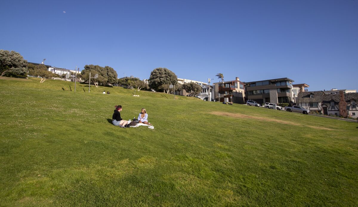 People sit in a wide, grassy space.