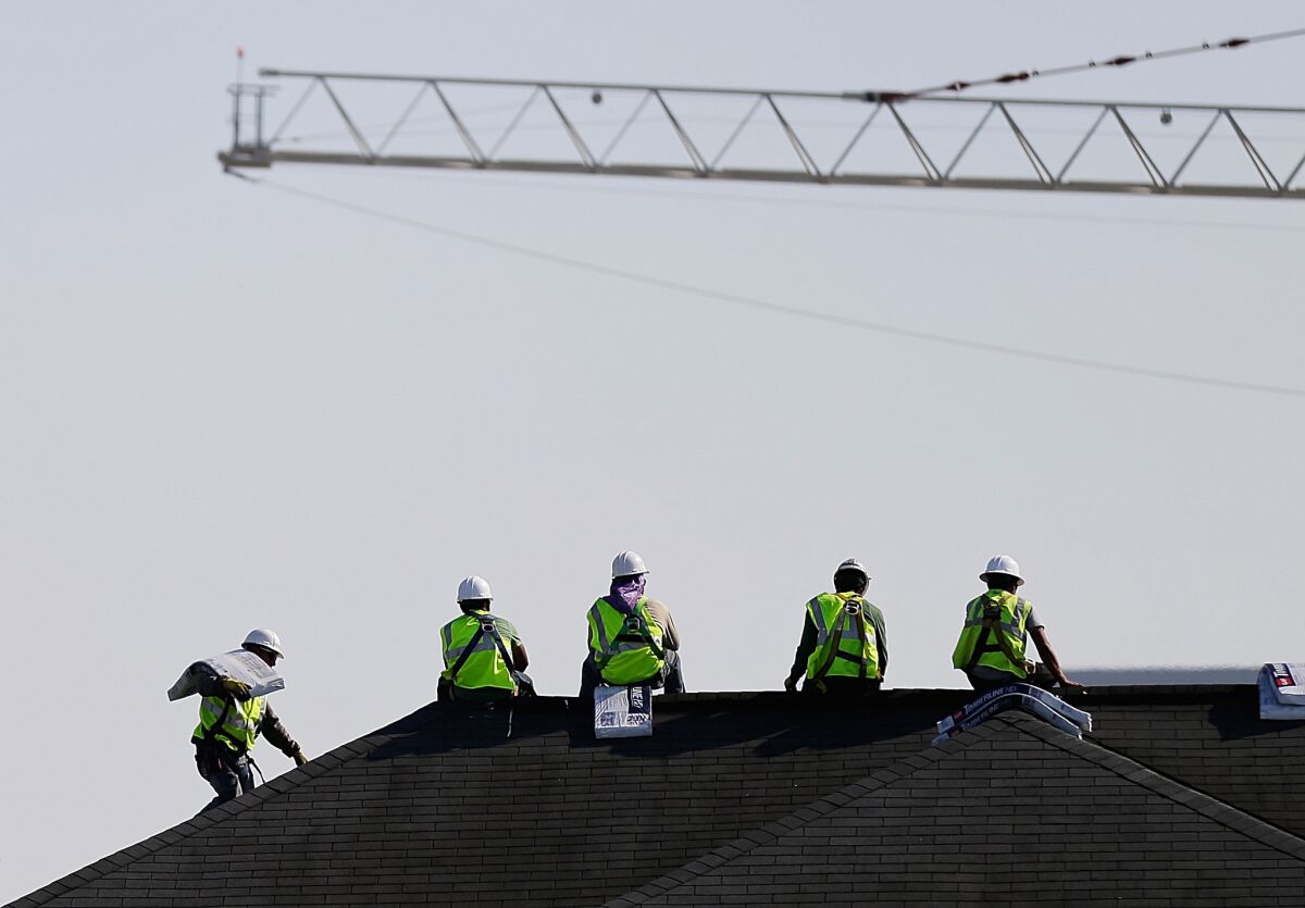 Construction workers rest while unloading supplies on a rooftop in Atlanta on March 23.