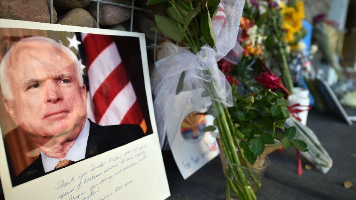 Photographs, flowers and notes gather at a makeshift memorial to John McCain outside his office in Phoenix on Aug. 26.