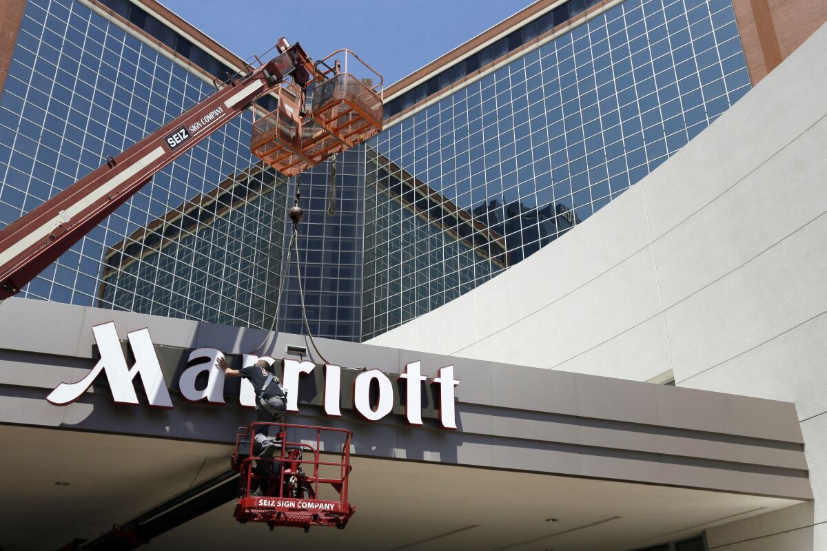 FILE - In this Tuesday, April 30, 2013, file photo, a man works on a new Marriott sign in front of the former Peabody Hotel in Little Rock, Ark. Marriott says its business is steadily improving, Monday, Aug. 10, 2020, with 91% of its hotels now reopen and business travel reemerging in China. (AP Photo/Danny Johnston, File)