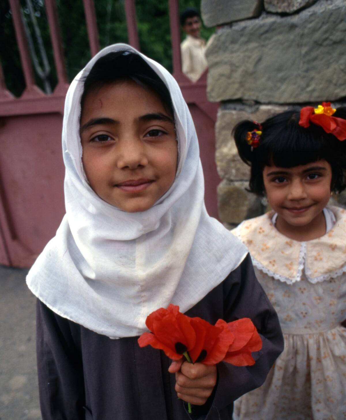 Schoolgirls greeted us south of Mashhad, bearing poppies. Iran, 1998.