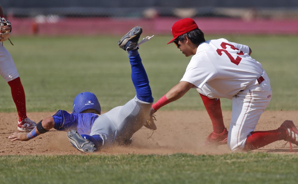 Fountain Valley's Tyler Arevalos is tagged by Fullerton's Kyle Kim (23) as he attempts a steal on Friday.