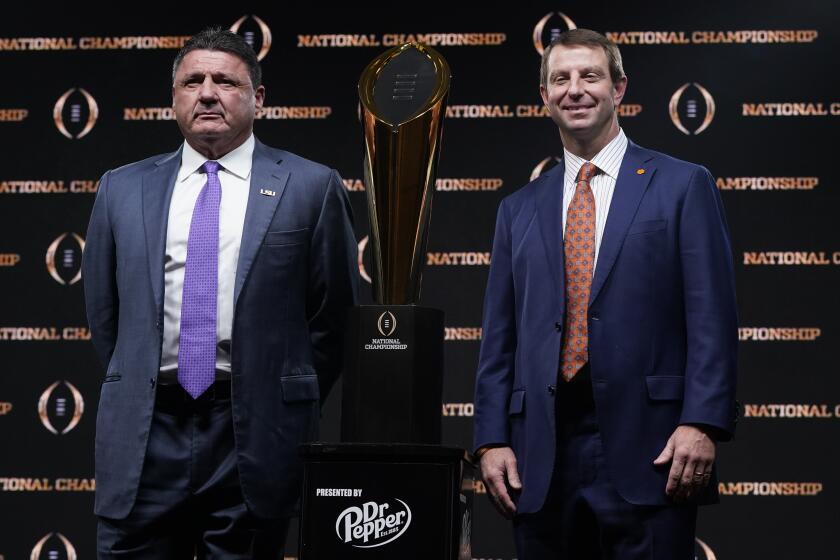 LSU head coach Ed Orgeron, left, and Clemson head coach Dabo Swinney pose with the trophy after a news conference for the NCAA College Football Playoff national championship game Sunday, Jan. 12, 2020, in New Orleans. Clemson is scheduled to play LSU on Monday. (AP Photo/David J. Phillip)